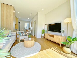 Un salon moderne avec un canapé, une table basse, un téléviseur et des plantes.
