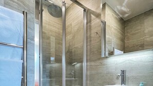 Une salle de bain moderne avec une douche à parois de verre, un lavabo blanc et un meuble-lavabo en bois.