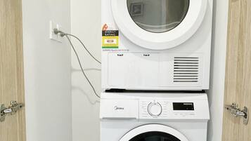 Máquina de lavar e secar empilhadas, com etiqueta de classificação de consumo de energia e água, ligadas a uma tomada de parede.