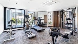 Ett modernt gym med konditionsmaskiner, en roddmaskin och en spegel.