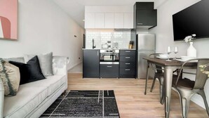 Una cocina moderna con comedor, paredes blancas y un televisor de pantalla plana.