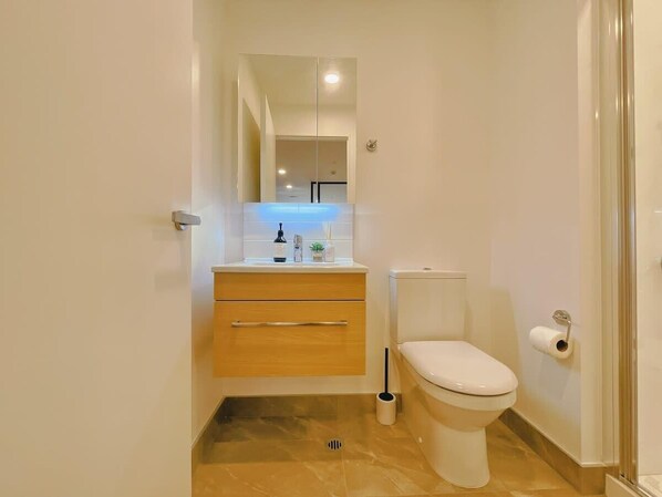 Un baño pequeño con inodoro, lavabo con espejo y un mueble bajo.