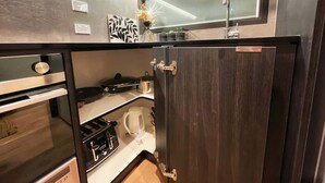 Una cocina compacta con horno integrado, cafetera y una pequeña ventana sobre el lavabo.