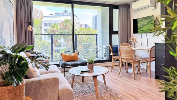 Una sala moderna con un sofá, una mesa de centro redonda y un comedor con sillas.