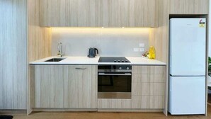 A compact kitchen with a built-in oven, a sink, and a refrigerator. - City & Ponsonby Center Side 2 BDR Townhouse vs AC (Auckland)