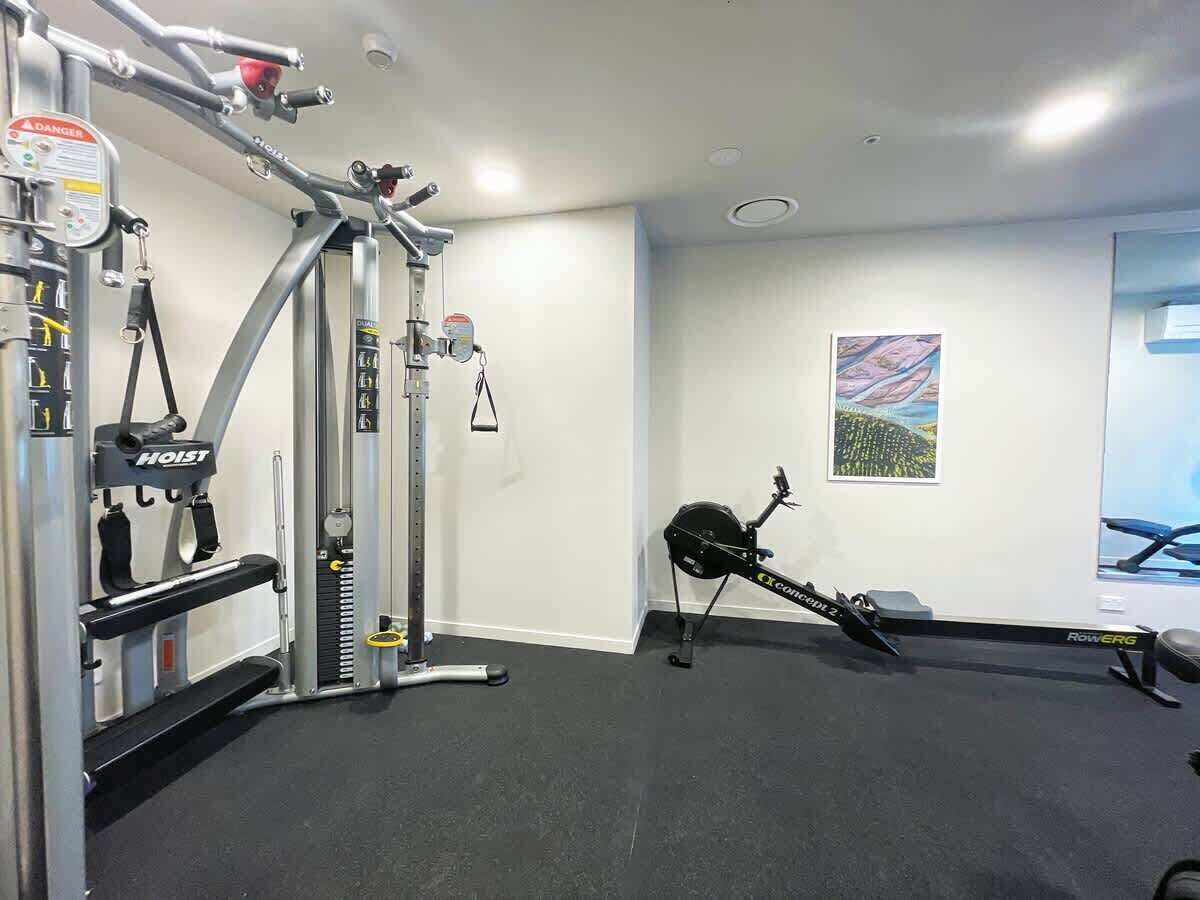 A gym with a rowing machine, a weight bench, and a cable machine.