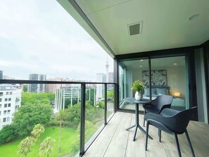 A balcony with a view of a cityscape, a table with chairs, and a potted plant. - Unique Luxury Amazing SkyTower Parkview & Parking (Auckland)
