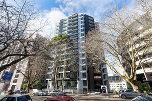 A multi-story building with a parking garage entrance, surrounded by leafless trees and parked cars.