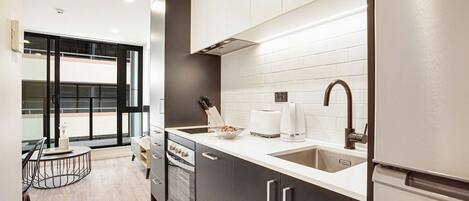 A modern kitchen with a large window, a built-in oven, and a refrigerator.
