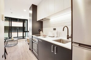 A modern kitchen with a large window, a built-in oven, and a refrigerator.