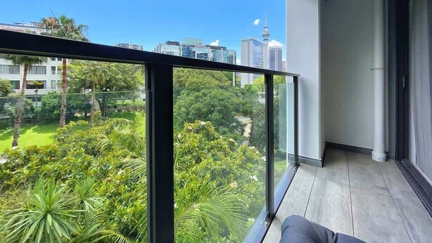 A balcony with a clear view of a city skyline and lush greenery.