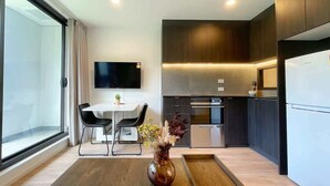 A modern kitchen with a dining area, a flat-screen TV, and a large window.