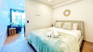 A modern hotel room with a large bed, a small seating area, and a view of the outside. - Aircon City Studio Near Skytower vs Pool Gym Sauna (Auckland)