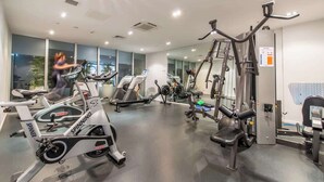 A gym with cardio machines, weight training equipment, and mirrors on the walls.
