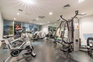 Ein Fitnessstudio mit Cardiogeräten, Krafttrainingsgeräten und Spiegeln an den Wänden.