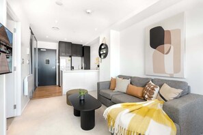A modern living room with a grey sofa, a black coffee table, and a yellow throw blanket. - Incredible City & Skytower View Near Queen St-Pool (Auckland)