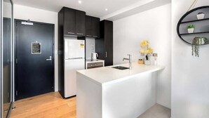 A modern kitchen with a white island, black cabinets, and a black door.