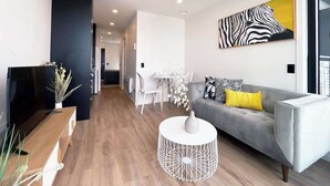 A modern living room with a grey sofa, a white coffee table, and a zebra-themed painting on the wall. - CBD Cozy Penthouse 1B Studio vs Pool Gym Sauna (Auckland)