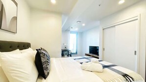 Una habitación de hotel moderna con una cama grande, un televisor y un escritorio con una silla.