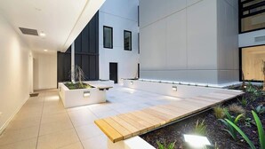 Un interior moderno con un largo banco de madera, macetas blancas y suelo de baldosas.