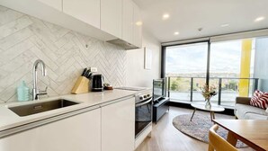 Cozinha moderna com revestimento de azulejos em padrão losango, forno embutido e uma grande janela com vista para o exterior.