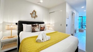 Une chambre d’hôtel avec un grand lit, une table de chevet, une lampe et une vue sur l’extérieur.