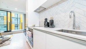 A modern kitchen with a large window, a built-in oven, and a stainless steel sink. - Central Stylish Comfy Studio with Swimming Pool (Auckland)