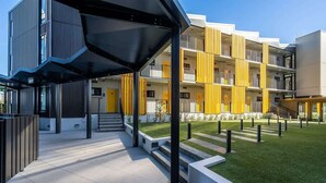 A modern apartment building with a courtyard, balconies, and a covered entrance area. - Central Stylish Comfy Studio with Swimming Pool (Auckland)