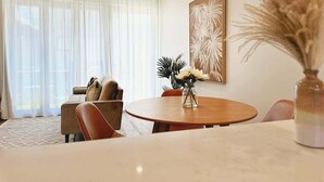 Ein modernes Wohnzimmer mit einem runden Holztisch, einer Couch und einem großen Fenster mit durchsichtigen Vorhängen.