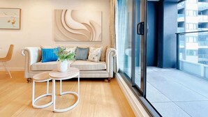 Ein modernes Wohnzimmer mit einer Couch, einem kleinen runden Tisch und einem großen Fenster mit Blick auf die Stadt.