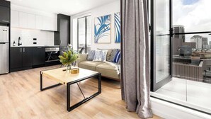 A modern apartment with a kitchen, living area, and a balcony with a city view.