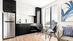 A modern kitchen with black cabinets, stainless steel appliances, and a dining area with a glass table and chairs.