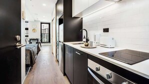 A modern kitchen with dark cabinets, a white countertop, and a built-in oven. - Beautiful Designed Apartment with Pool Gym Sauna (Auckland)