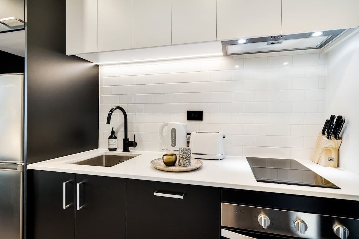 Een moderne keuken met een dubbele spoelbak, een koffiezetapparaat, een broodrooster en een messenblok.