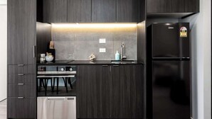 A modern kitchen with dark wood cabinets, a stainless steel refrigerator, and a built-in oven.