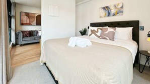 Ett modernt hotellrum med en stor säng, en soffa och en tavla på väggen.