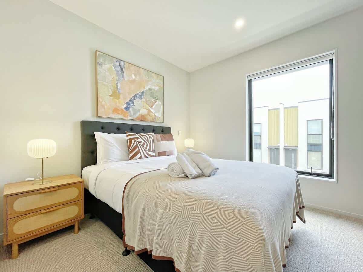 Une chambre à coucher avec un lit, une table de chevet et une grande fenêtre.