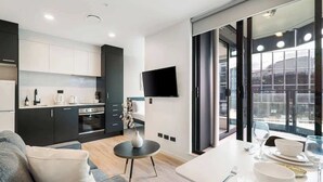 A modern kitchen with dark cabinets, a white countertop, and a flat-screen TV mounted on the wall. - Modern Aircon 1BD Nearby Skytower - Pool Sauna Gym (Auckland)