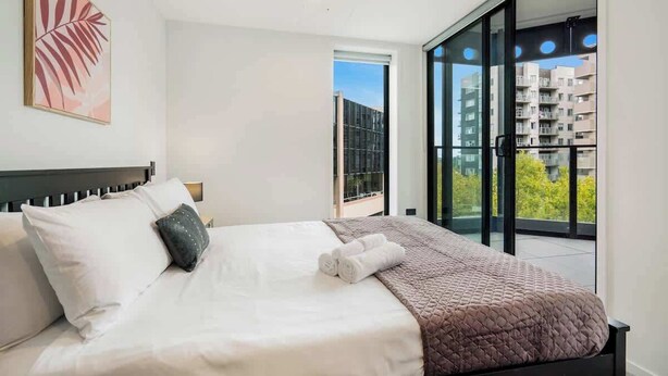 A modern hotel room with a bed, a large window, and a view of a building. - Modern Aircon 1BD Nearby Skytower - Pool Sauna Gym (Auckland)