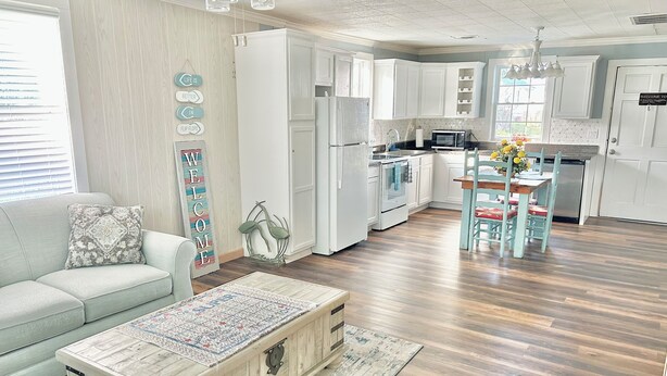 A modern kitchen with white cabinets, a central island, and a dining area with a table and chairs. - Charming 2-bedroom cottage, sleeps 2-4, with WiFi & AC in adorable Guntersville (Guntersville)