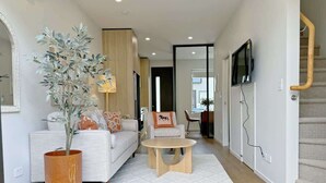A modern living room with a sofa, coffee table, and a large potted plant.
