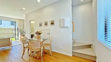 Un interior moderno con comedor, escalera y vistas al exterior.