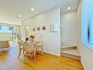 A modern interior with a dining area, staircase, and a view of the outdoors.