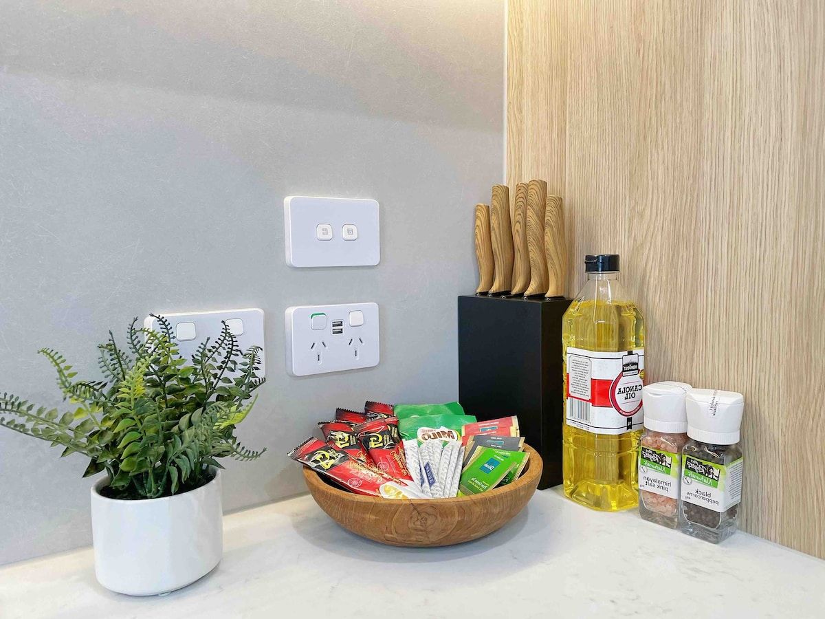 A kitchen counter with a potted plant, a bowl of snacks, a bottle of cooking oil, and a spice rack.