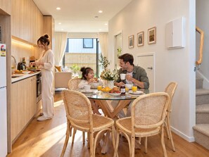 Una cocina moderna con comedor, piso de madera y una escalera.