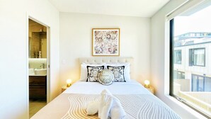 Habitación de hotel con cama, ventana grande y vistas al exterior.