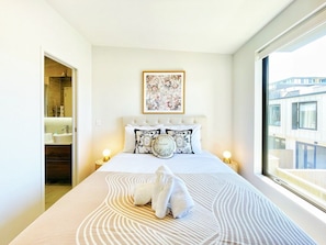 Habitación de hotel con cama, ventana grande y vistas al exterior.
