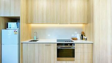 Una cocina compacta con horno empotrado, lavamanos y refrigerador.