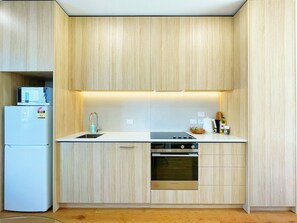 A compact kitchen with a built-in oven, a sink, and a refrigerator.