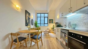 Eine moderne Küche mit Einbauofen, ein Essbereich mit rundem Tisch und Stühlen sowie ein Fenster für natürliches Licht.